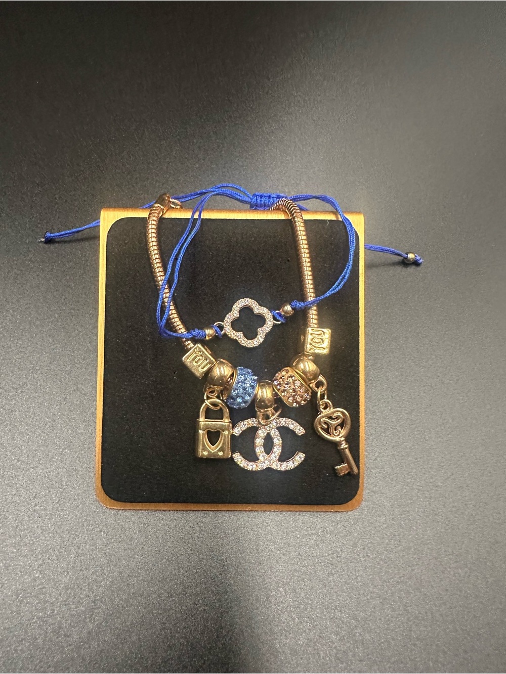 Unlisted Gold-Tone Charm Bracelet with Blue Cord and Crystal Logo Charm